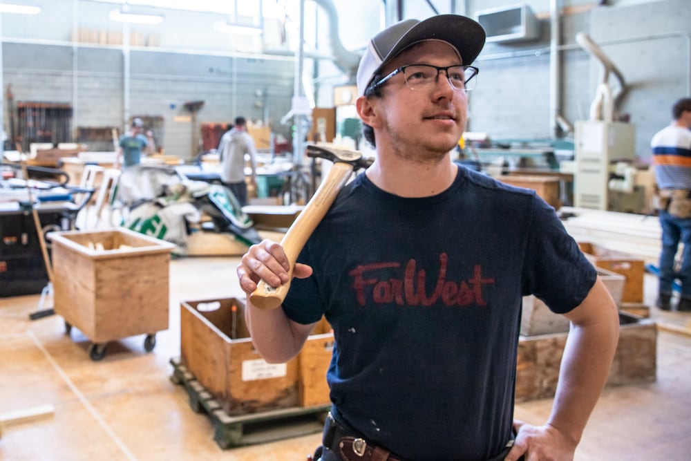 Carpentry student resting with hammer on shoulder