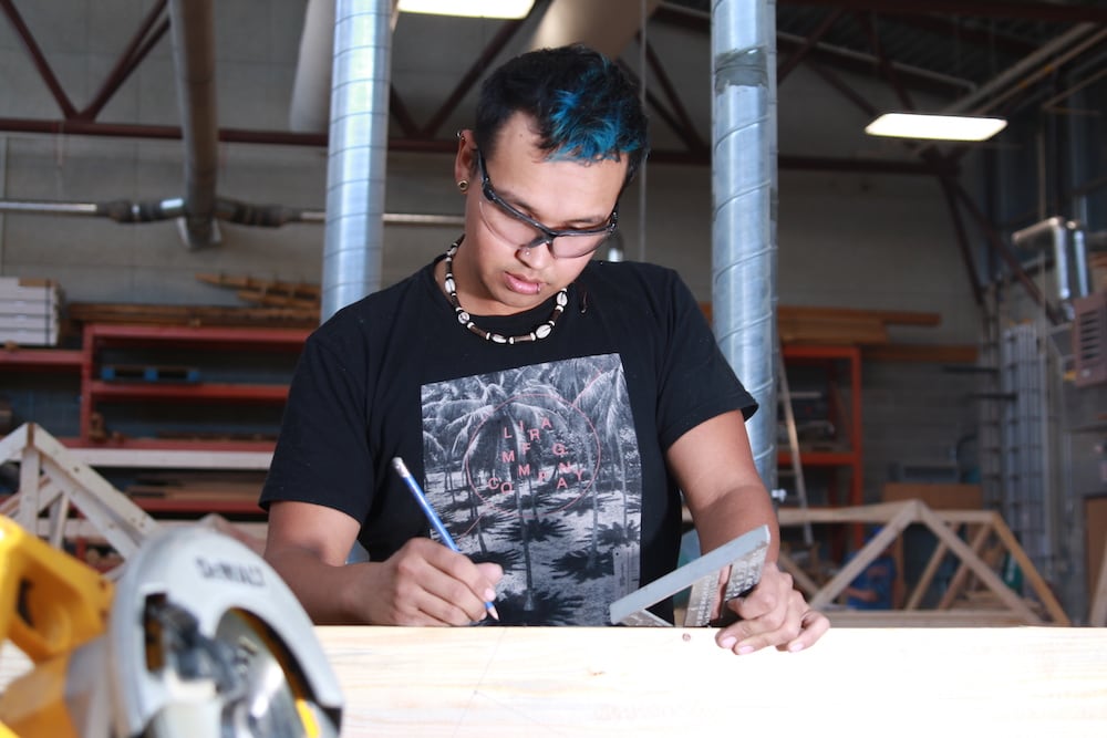 Carpentry student marking wood with ruler and pencil